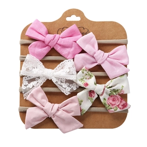 Close-up of 5-piece floral and lace bow headbands for babies on a kraft display card