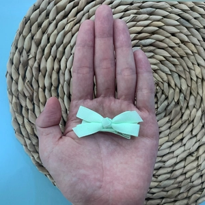 Close-up of mint green floral bow hair clip showing grosgrain ribbon texture and metal clip
