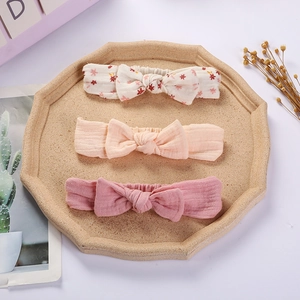Three-pack of baby cotton bow headbands with floral and solid colors on a display tray