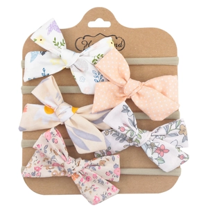 Detailed set of 5 baby bow headbands with floral and polka dot patterns on display card