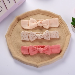 Detail of three soft cotton muslin baby headbands with cute rabbit ear bows in a tray