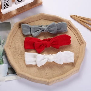 Detailed view of three-piece muslin baby headbands in grey, red, and cream white colors