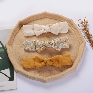Three-piece baby bow headbands featuring muslin texture and floral patterns on a tray