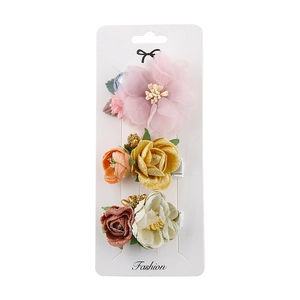 Détail d'un lot de 3 barrettes à fleurs en tissu sur une carte de présentation blanche