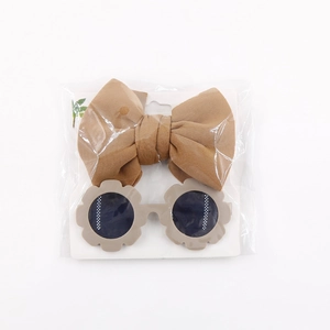 Close-up of brown bow headband and flower sunglasses set in transparent packaging