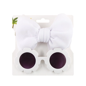 Detail of baby set with white oversized bow headband and daisy-shaped sunglasses on card