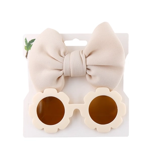 Detail of cream oversized bow headband and sunflower-shaped sunglasses on white display card