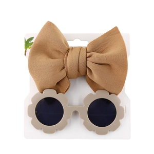 Detail of light brown bow headband and beige flower sunglasses on display card
