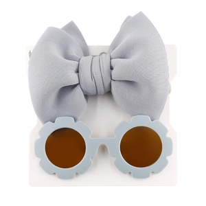 Detailed view of kids floral sunglasses and gray bow headband set on white display card