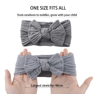Détail macro du bandeau bébé en maille grise montrant son élasticité jusqu'à 46 cm