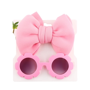 Detailed view of pink bow headband and floral sunglasses on a display card