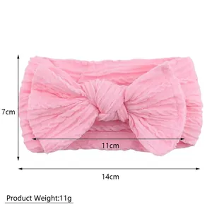 Détail du bandeau bébé en nylon rose avec texture côtelée et grand nœud, 14 cm x 7 cm
