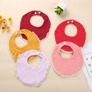 Detailed view of soft cotton gauze baby bibs with pom-pom trim and adjustable snaps