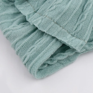 Détail macro du motif en maille torsadée vert menthe et bord-côte du bandeau bébé