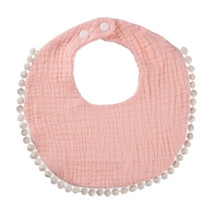 Close-up of pink cotton gauze baby bib featuring white pom-pom trim and adjustable snap buttons