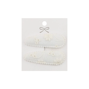 Detail showing two-piece set of cream fabric hair clips with floral embroidery and wavy edges