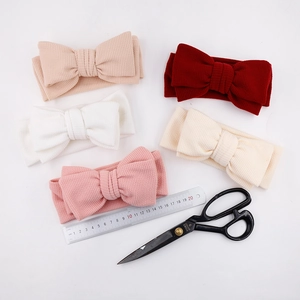 Vue à plat de cinq bandeaux bébé à nœuds en maille côtelée rouge, beige et rose pastel