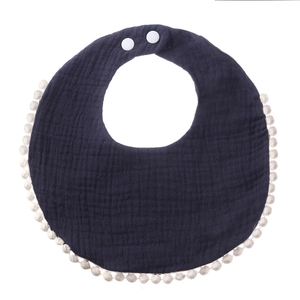 Detail of navy cotton gauze baby bib with pom-pom trim and adjustable snap buttons