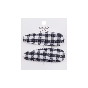 Detail of two black and white gingham fabric hair clips on a white display card