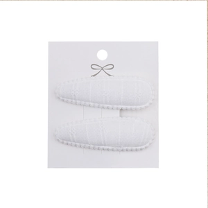 Detailed close-up of white fabric teardrop hair clips with elegant scalloped lace edges