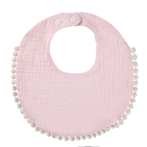 Close-up of pink cotton gauze baby bib with pompom lace and adjustable snap buttons