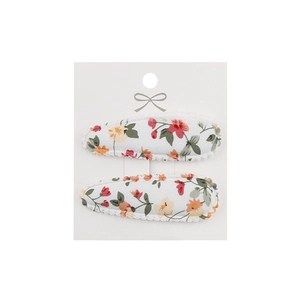 Detail of two floral embroidery cloth hair clips on a decorative white display card