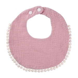 Detail of pink cotton baby bib with decorative white pom-pom trim and adjustable snap buttons