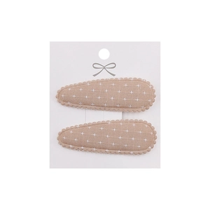Close-up of two drop-shaped fabric hair clips with white floral embroidery and scalloped edges