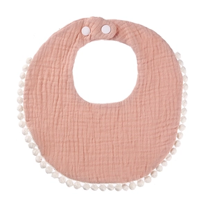 Detail of pink cotton muslin baby bib with pom-pom trim and adjustable snap buttons
