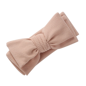 Détail de la texture en maille côtelée et du nœud papillon de ce bandeau pour bébé