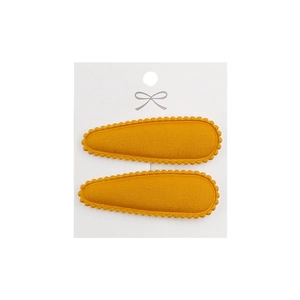 Close-up of yellow embroidered fabric hair clips with wave edges on a display card