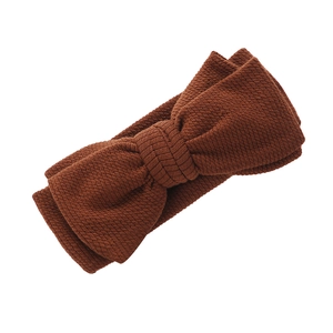 Détail du tricot côtelé et du grand nœud sur le bandeau pour bébé de couleur caramel