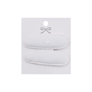 Detailed macro view of two white cotton hair clips with embroidered floral patterns on a card