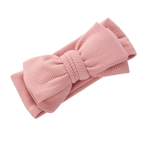 Gros plan du bandeau bébé rose en maille gaufrée avec grand détail de nœud décoratif