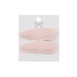 Detailed macro view of two light pink lace-covered teardrop hair clips with embroidery