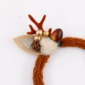Close-up of Christmas reindeer headband featuring pine cones and berries with plush texture