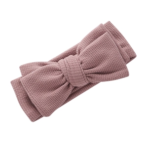 Détail du tissu côtelé doux et du grand nœud sur ce bandeau pour bébé rose