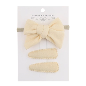 Detailed set of beige faux cashmere bow headband and two oval clips on white display card