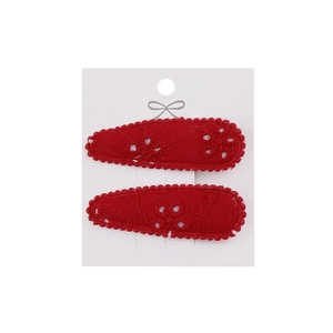 Detailed macro of red floral embroidery and scalloped edges on two teardrop hair clips