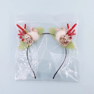Close-up of Christmas deer antler headband with red antlers, white pom poms, and fabric flowers