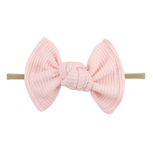 Macro detail of pink waffle fabric bow headband with high elasticity for infants