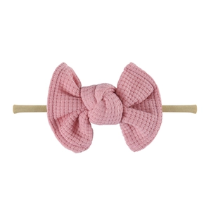 Detail of pink waffle texture bow on a beige high elasticity baby headband
