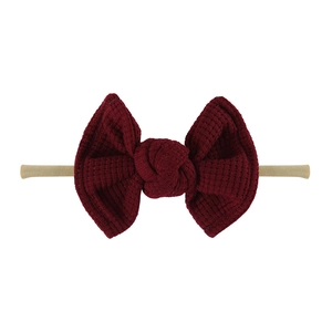 Detailed close-up of dark red waffle textured bow on a nude nylon baby headband