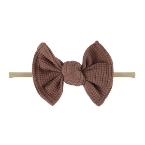 Detail showing brown waffle knit bow on elastic nylon baby headband over white background