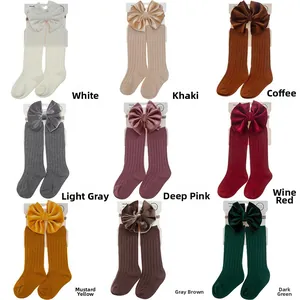 Detail view of nine colors of baby ribbed socks with large velvet bows in packaging
