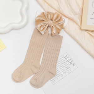 Detail of khaki ribbed cotton baby socks and velvet bow headband on decorative tray