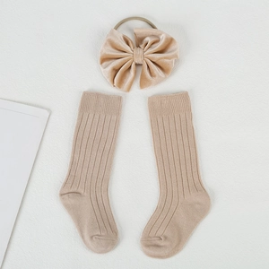 Detail view of ribbed cotton baby socks and a matching velvet bow headband in beige