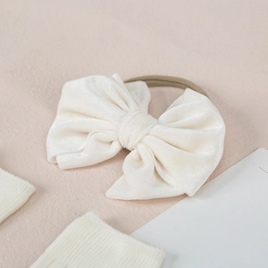 Close-up of creamy white velvet bow headband with highly elastic skin-tone strap