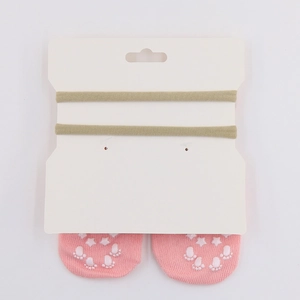 Pink non-slip baby floor socks with olive green elastic headbands on display card