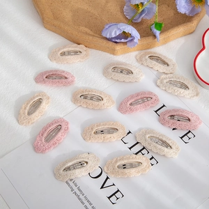 Detail of soft pink and off-white cotton knit lace snap hair clips with cozy texture